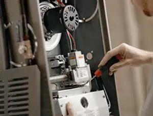 Furnace repair technician inspecting internal components and wiring in Tacoma, WA