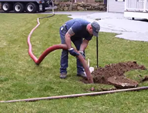 Septic pumping technician servicing a residential septic tank with a vacuum hose in Tacoma, WA