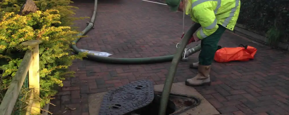 Septic tank cleaning technician servicing a septic tank with a vacuum hose in Tacoma, WA