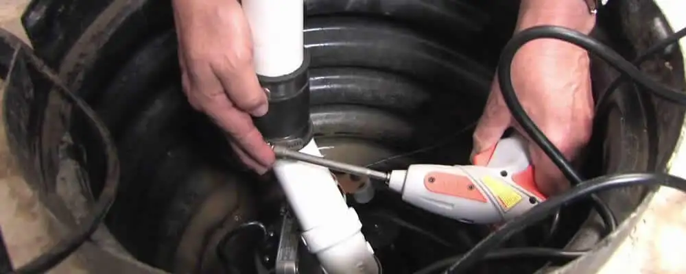 Sump pump installation technician connecting PVC discharge piping in Tacoma, WA